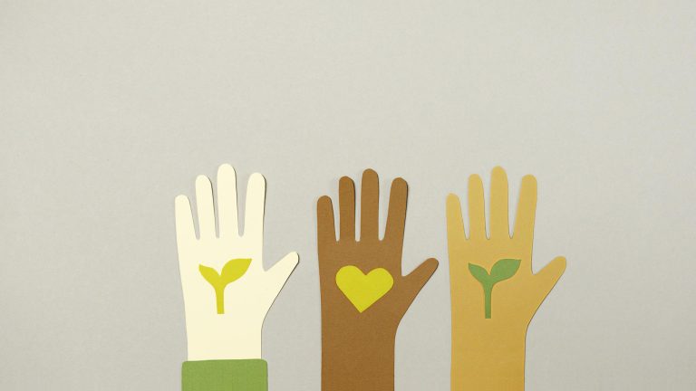 Three paper cutout hands with eco-friendly symbols, representing unity and sustainability.